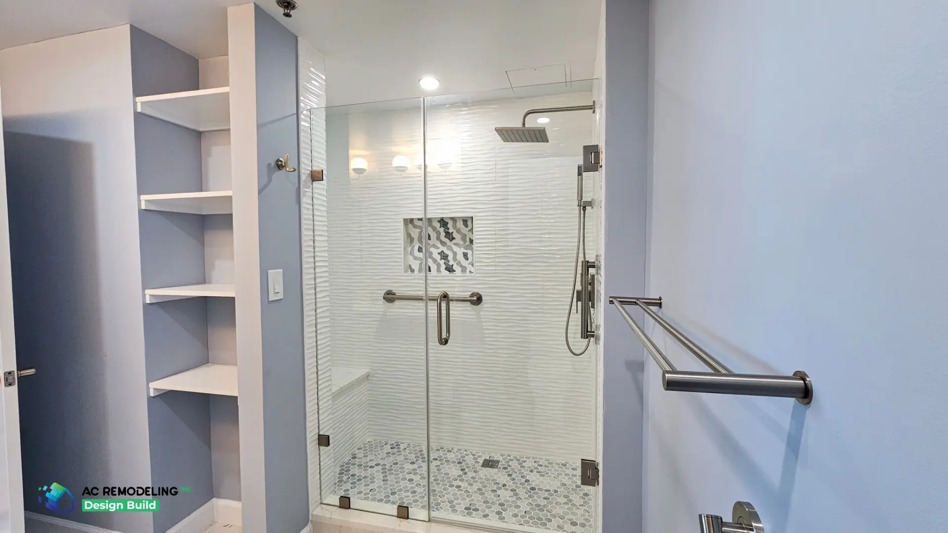 Frameless glass shower with wave-texture tile, mosaic niche, hex pebble floor and built-in shelving