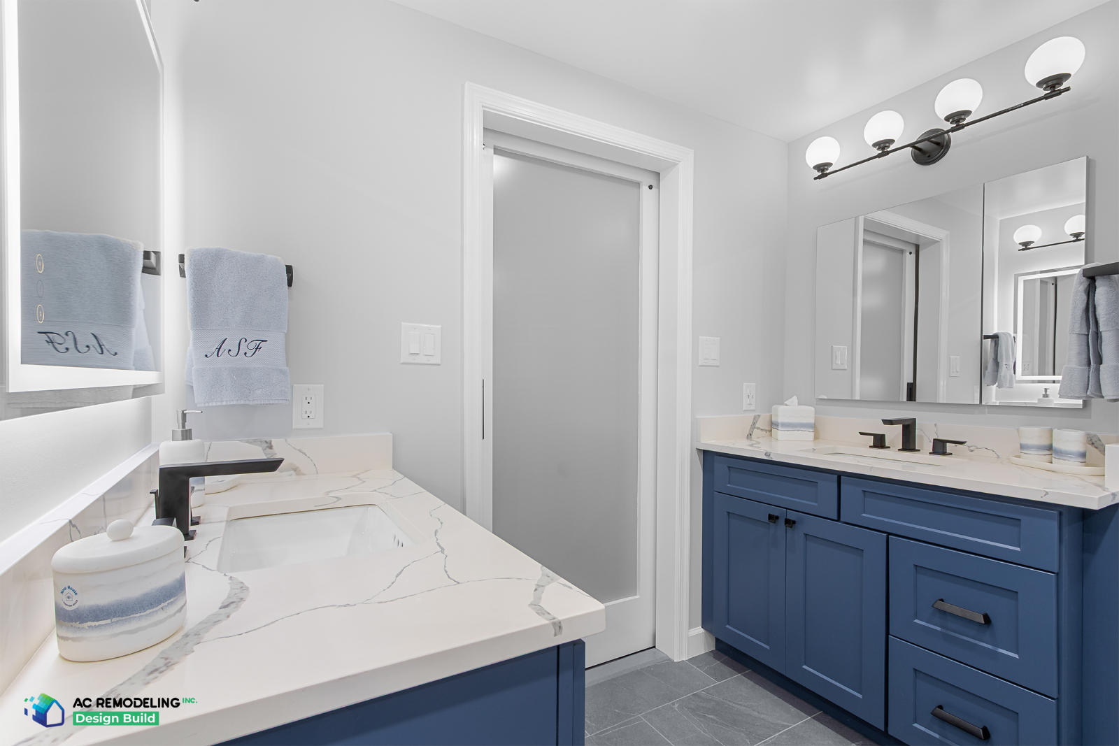 Navy double vanities with quartz counters, black hardware and frosted pocket door