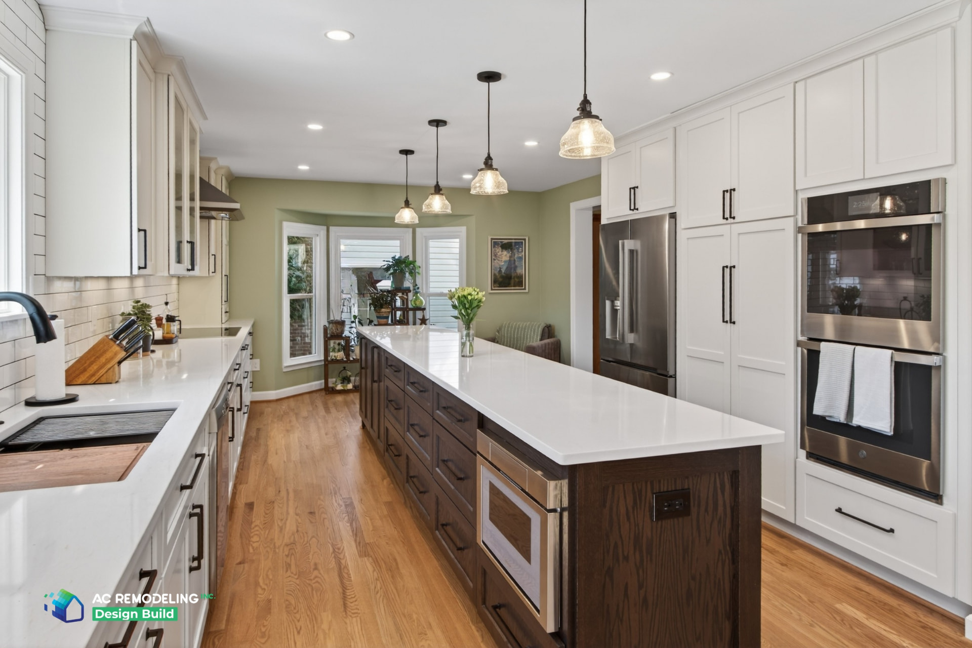 Kitchen looking toward bay window breakfast nook with glass pendants over the quartz island
