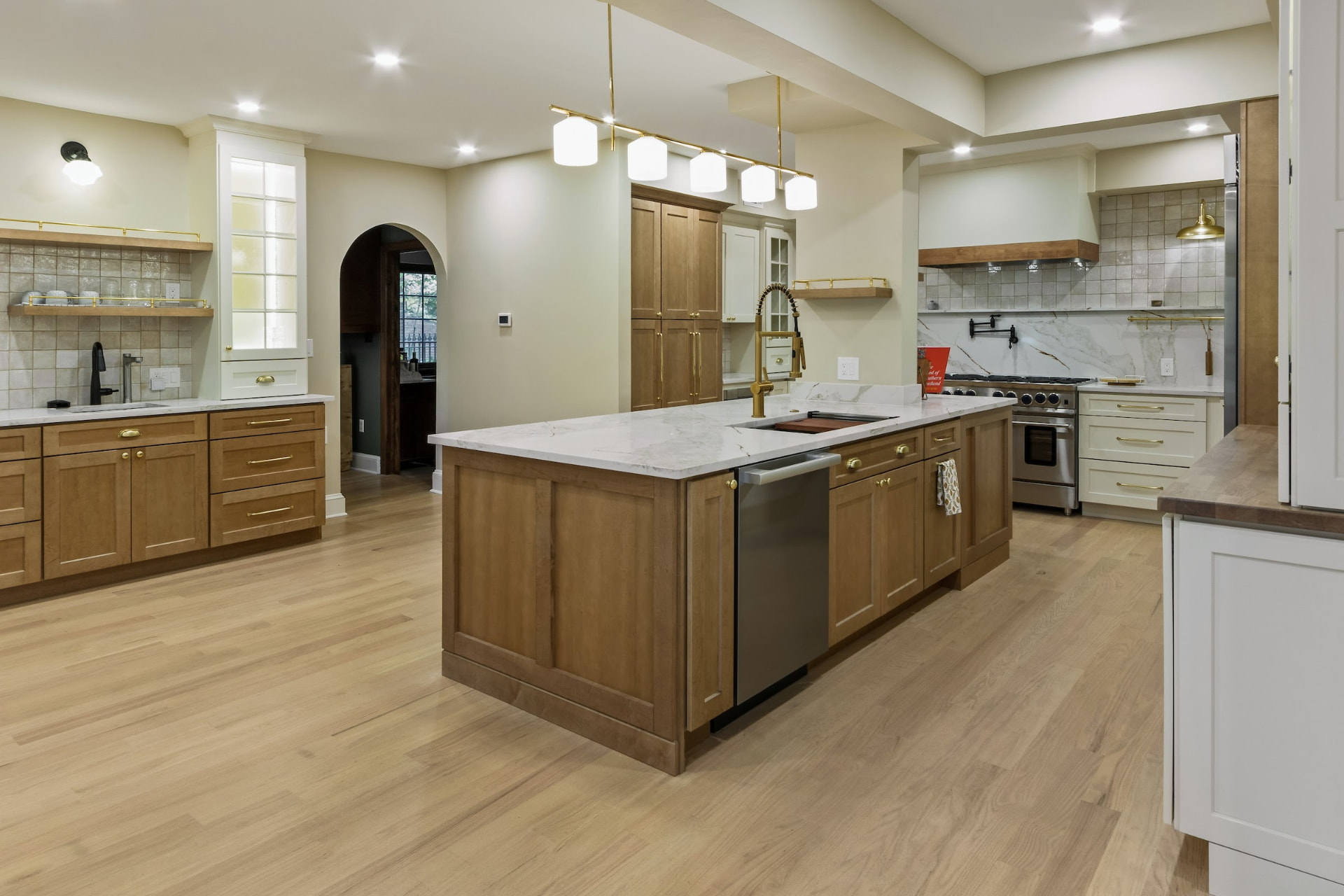 Transitional kitchen with stained wood island, marble counters and brass fixtures