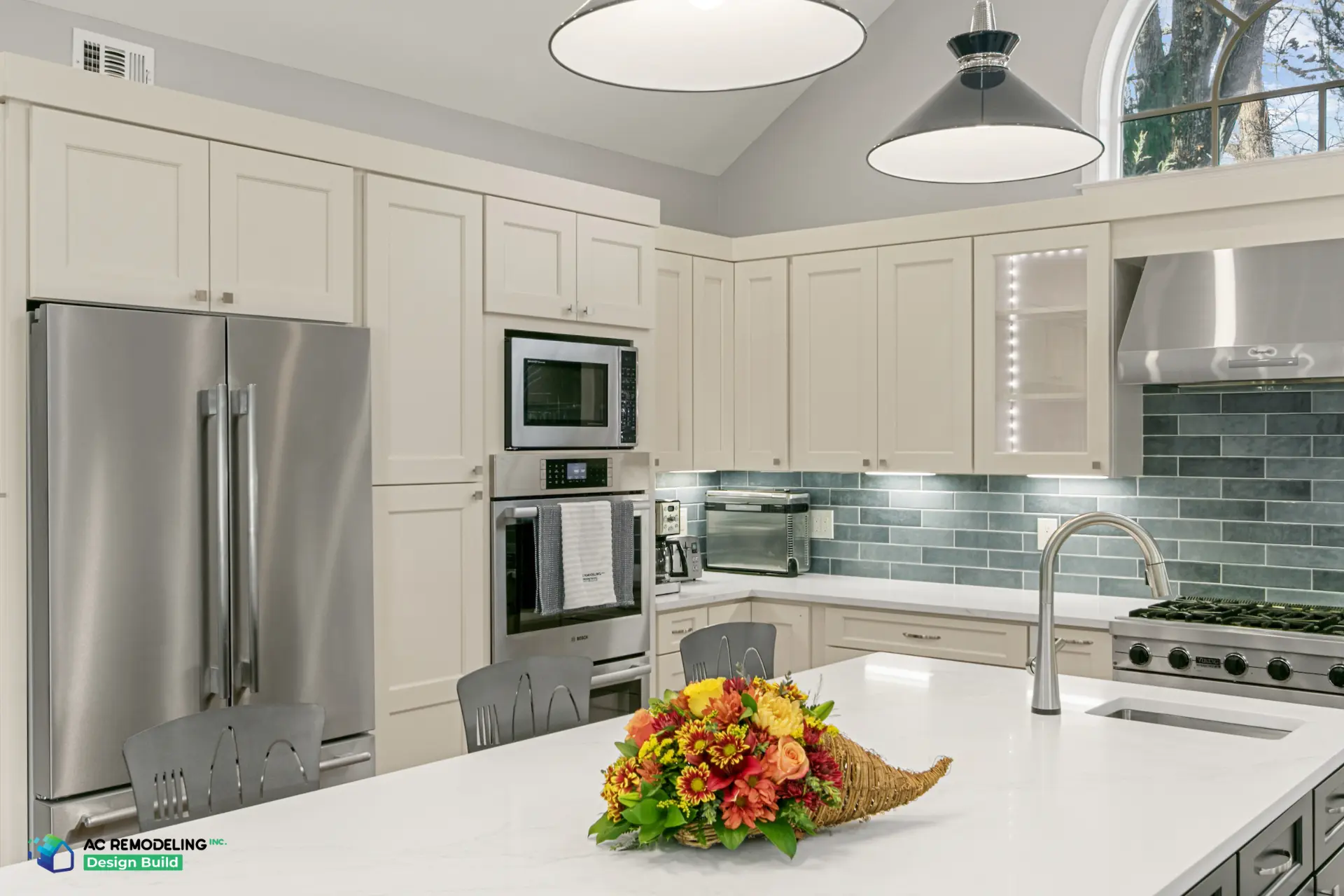 Cream cabinetry with paneled refrigerator, double wall ovens and lit glass-front uppers