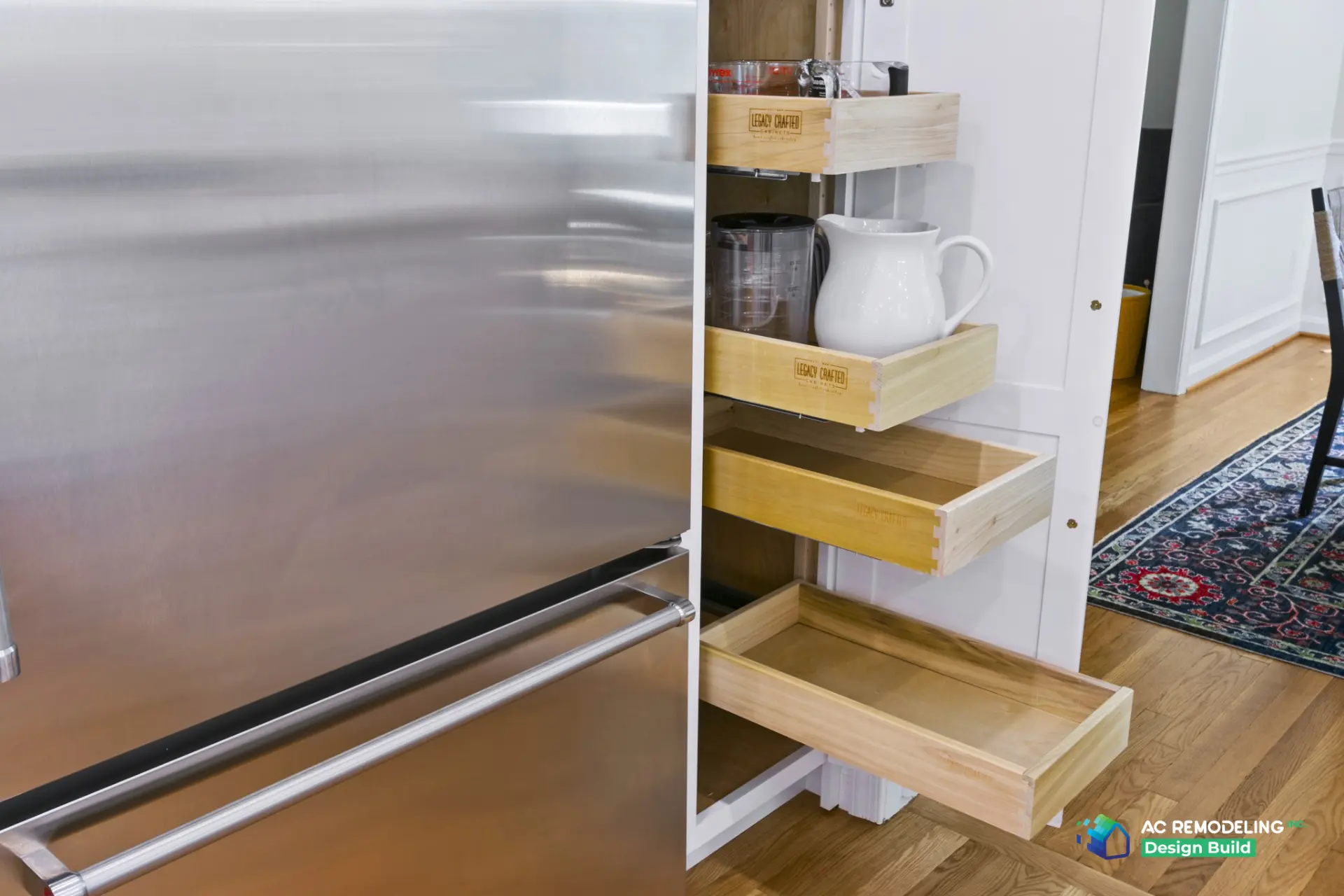 Custom pull-out pantry drawers in white cabinetry beside stainless refrigerator