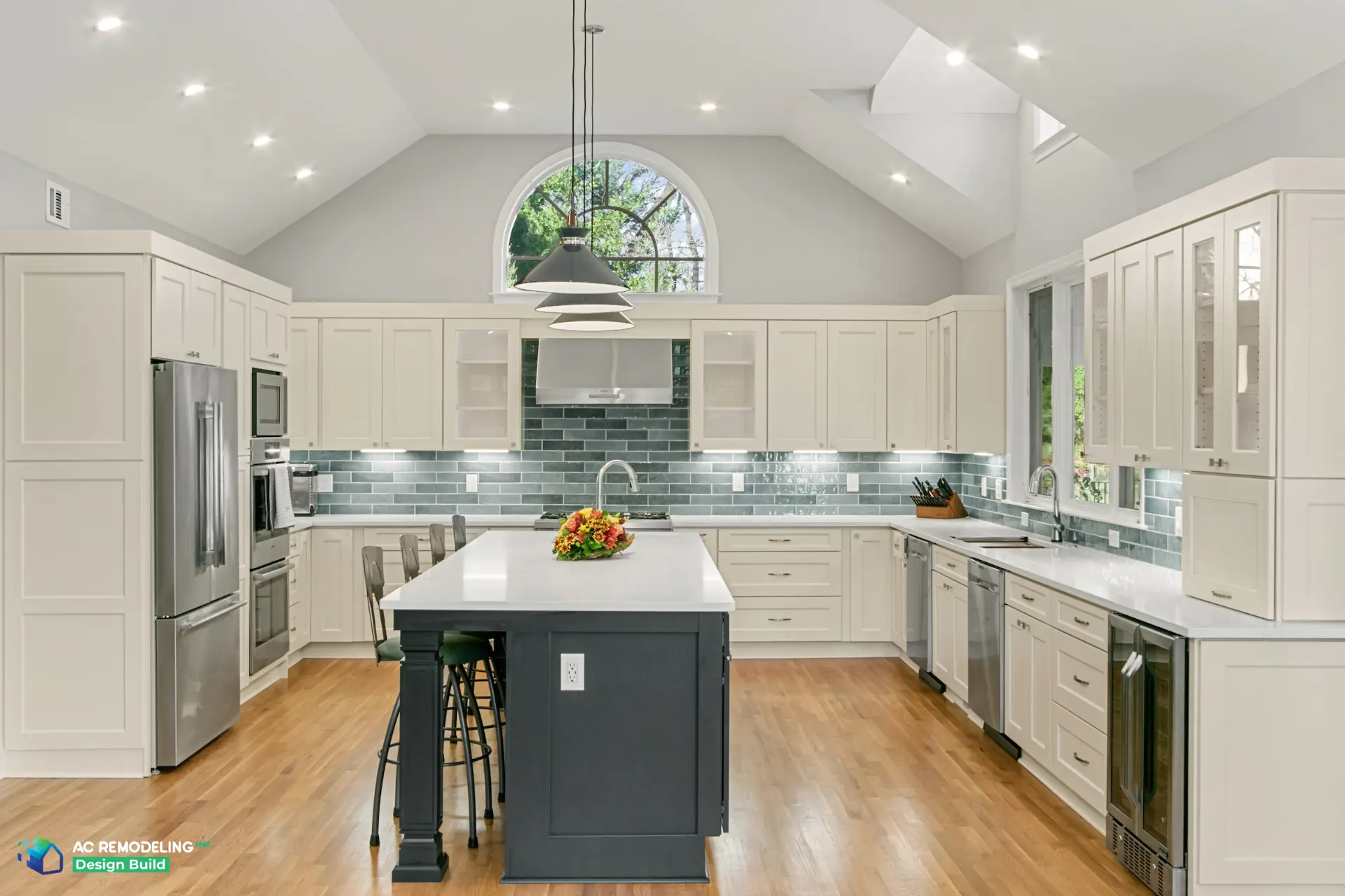 Symmetrical view of the kitchen under the arched window with pendant lights over the charcoal island