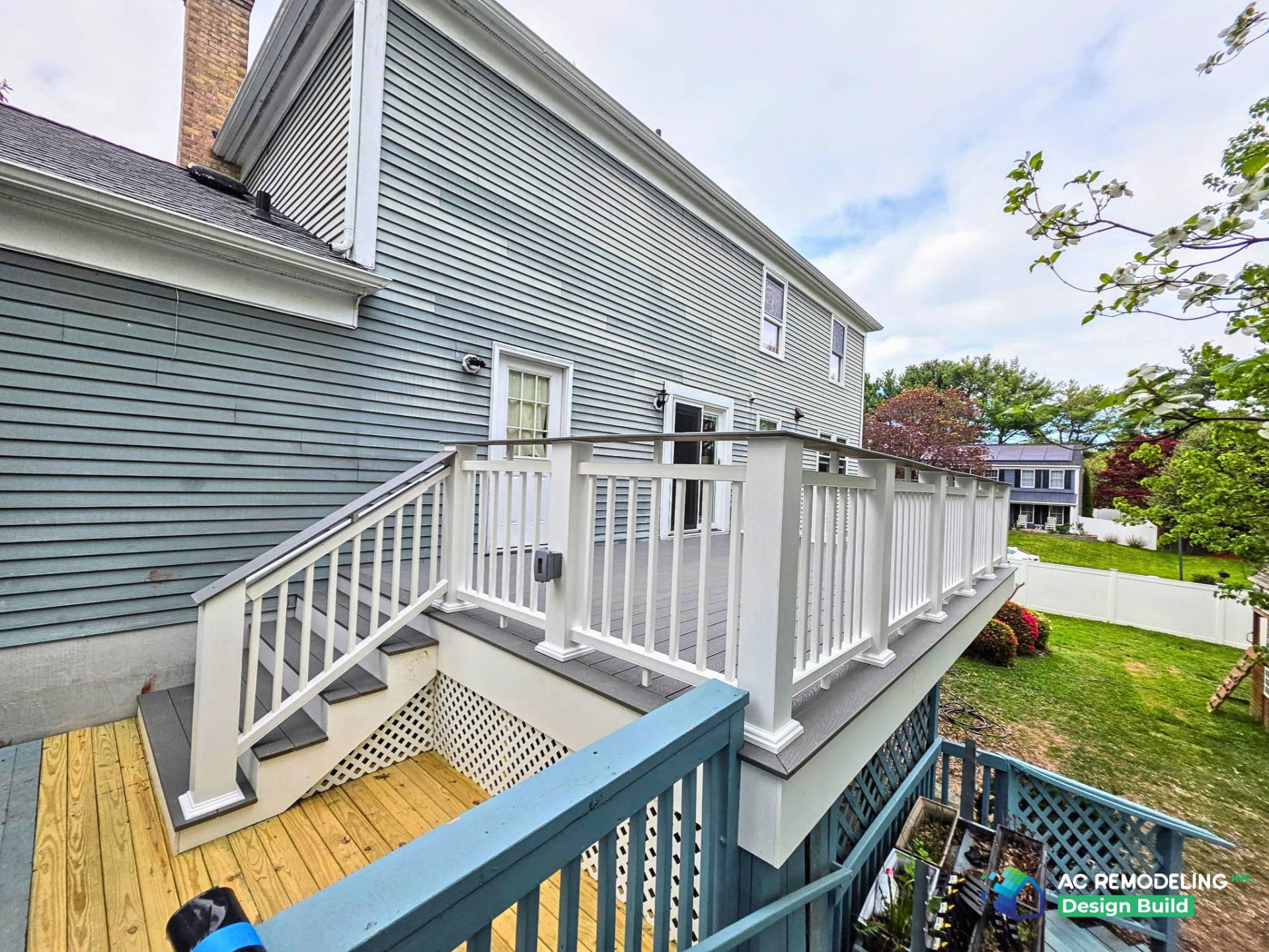 New composite deck with white railing and stairs on a gray sided home