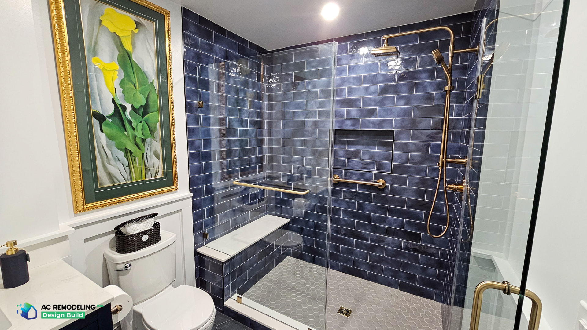 Blue tiled walk-in shower with bench, niche, brass rain shower and frameless glass enclosure