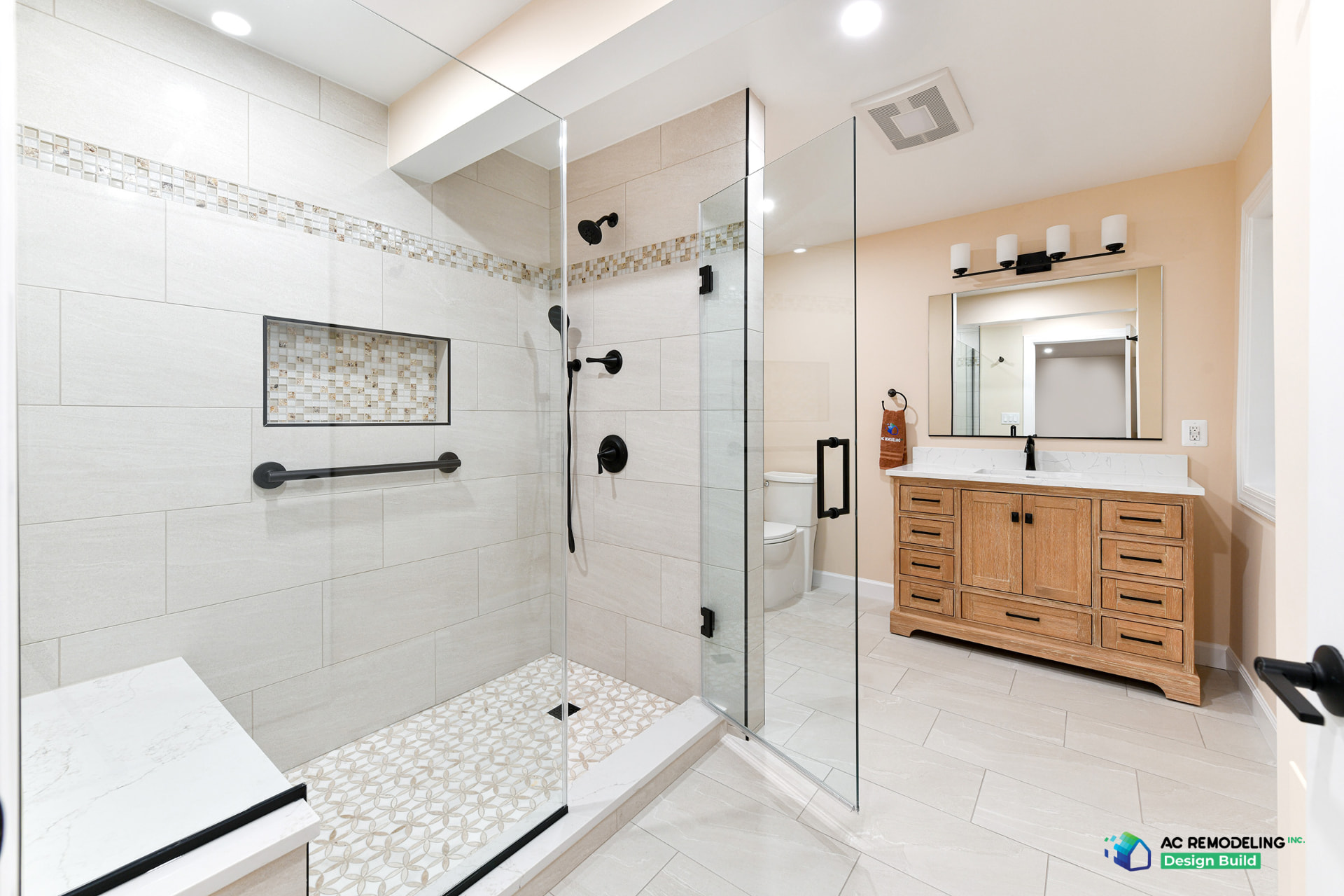 Accessible basement bathroom with glass shower, mosaic niche, black fixtures and wood vanity