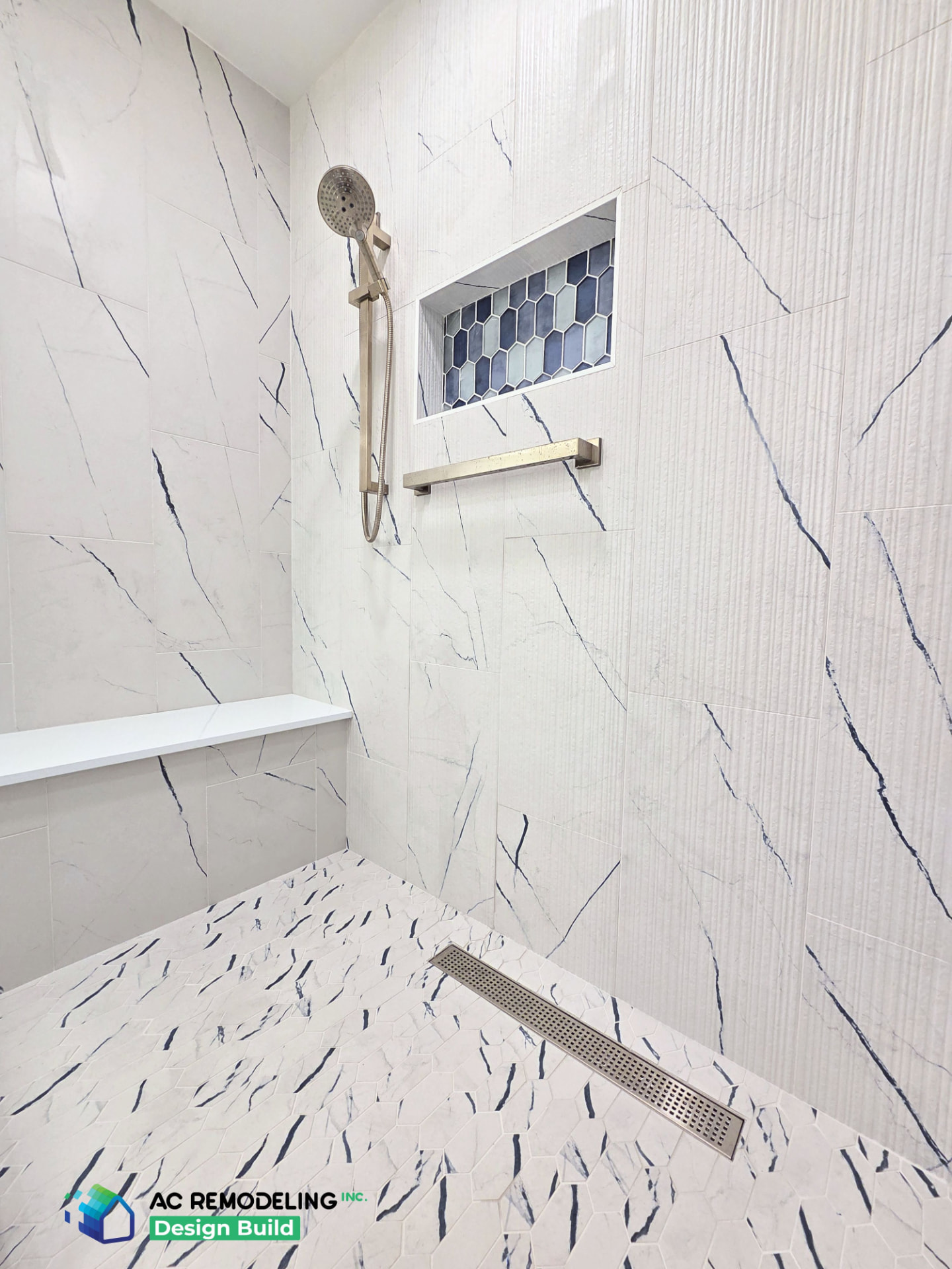 Shower interior with quartz bench, hand shower and blue picket-tile niche above the linear drain