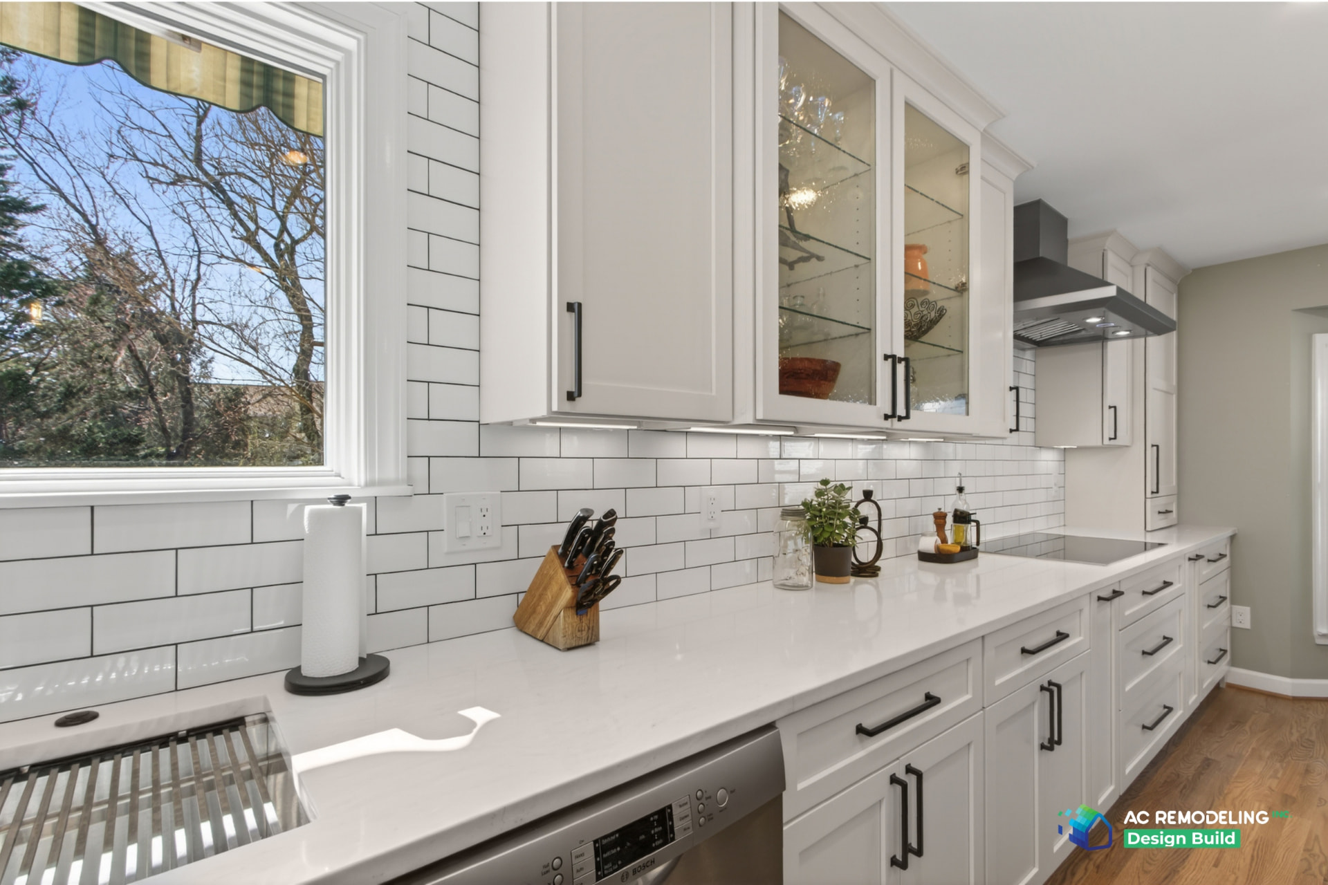 Kitchen run with quartz countertops, glass-front cabinets and subway tile