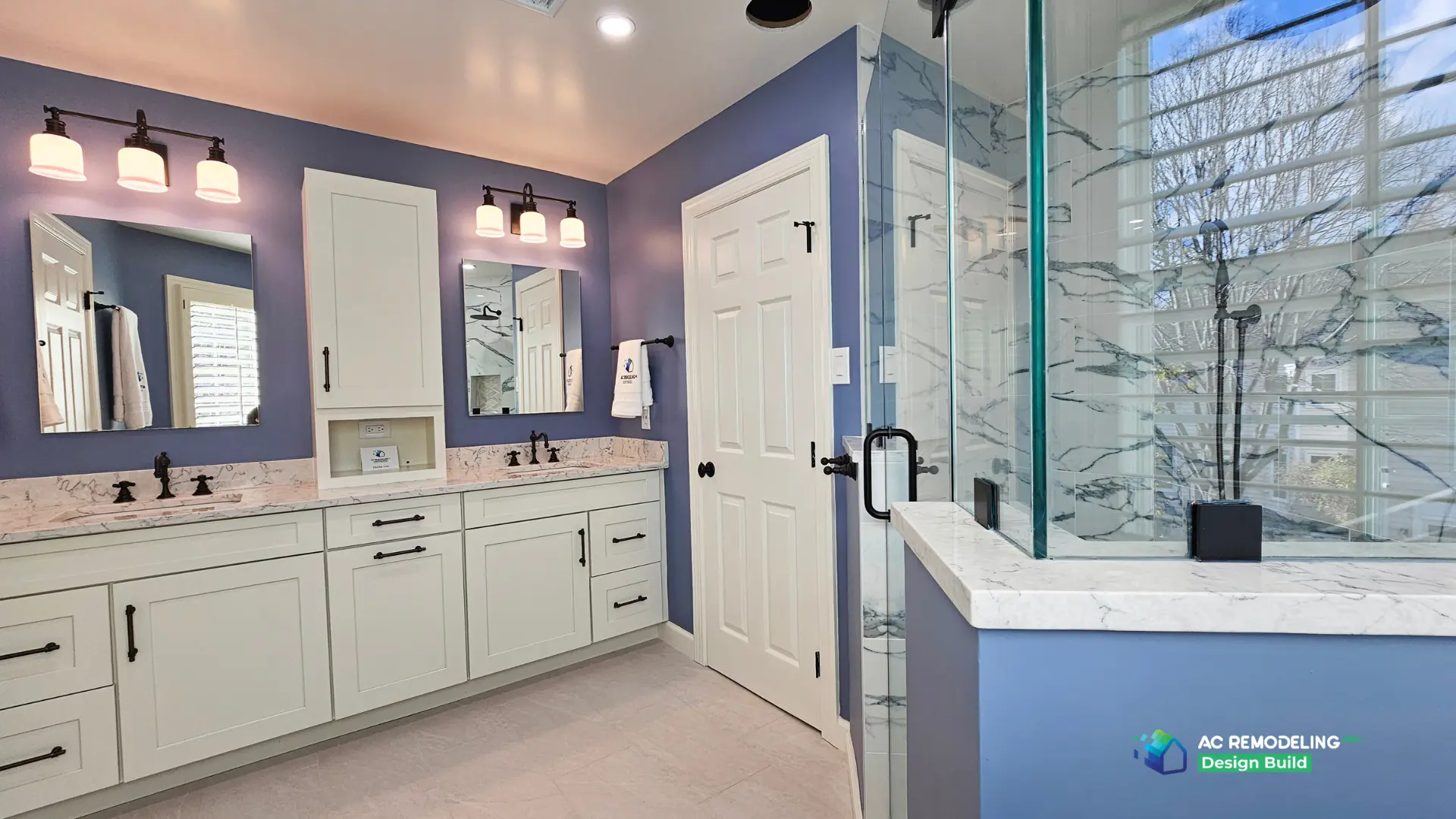 Primary bath with double vanity and glass shower framed by a shuttered window