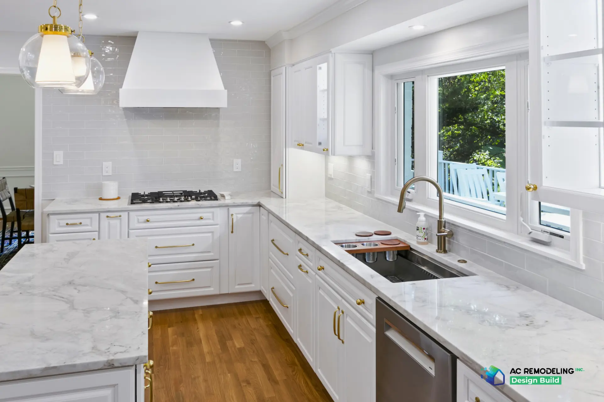 Gas cooktop under white hood with workstation sink and brass faucet