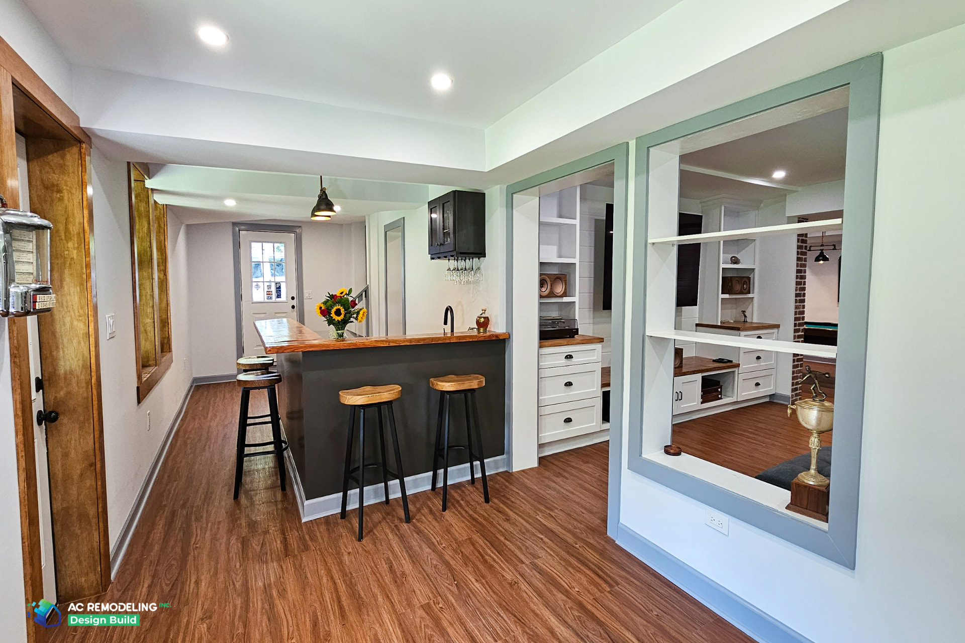 Custom basement wet bar with live-edge wood counter, charcoal cabinetry and hanging stemware storage