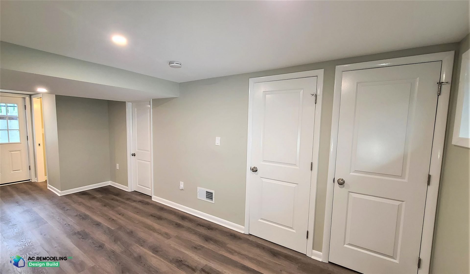Modern basement bathroom with dual faucet farmhouse sink, bold red step stools for kids, and white subway tile walls for a clean, family-friendly design.