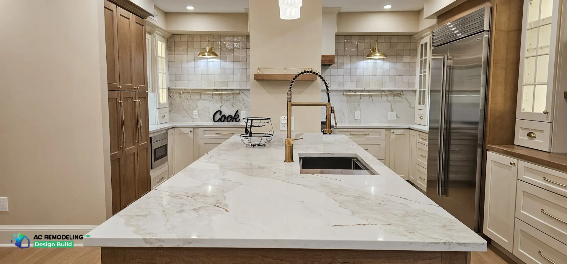 Quartzite waterfall island with brass gooseneck faucet and workstation sink