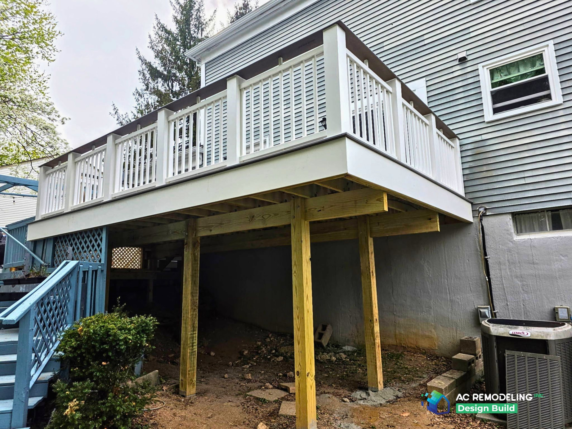 Elevated deck with white railing and new structural posts behind a home