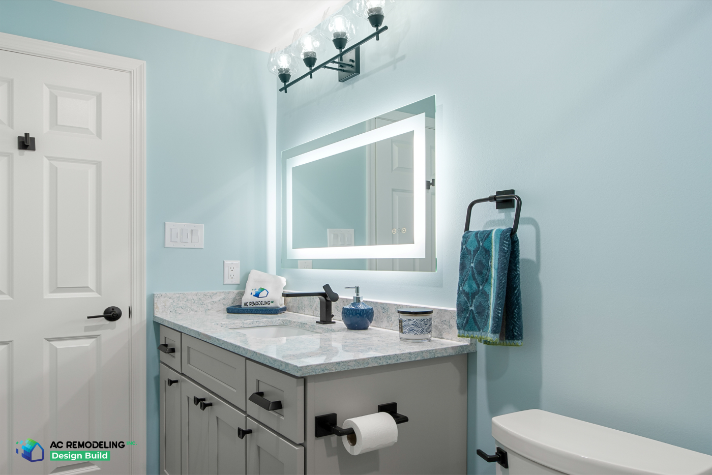 Powder-style vanity with backlit mirror, glass globe sconces and matte black faucet