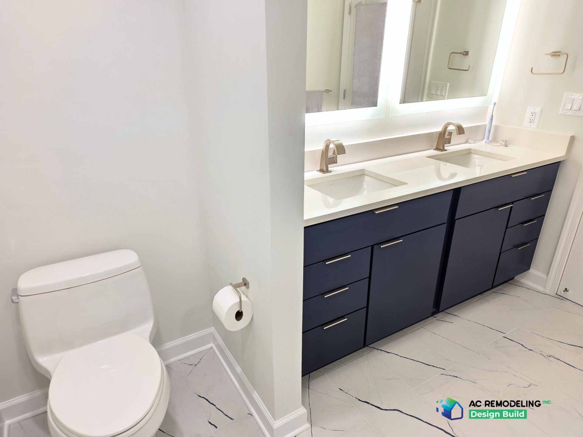 Navy double vanity beside the water closet with marble-look tile floor