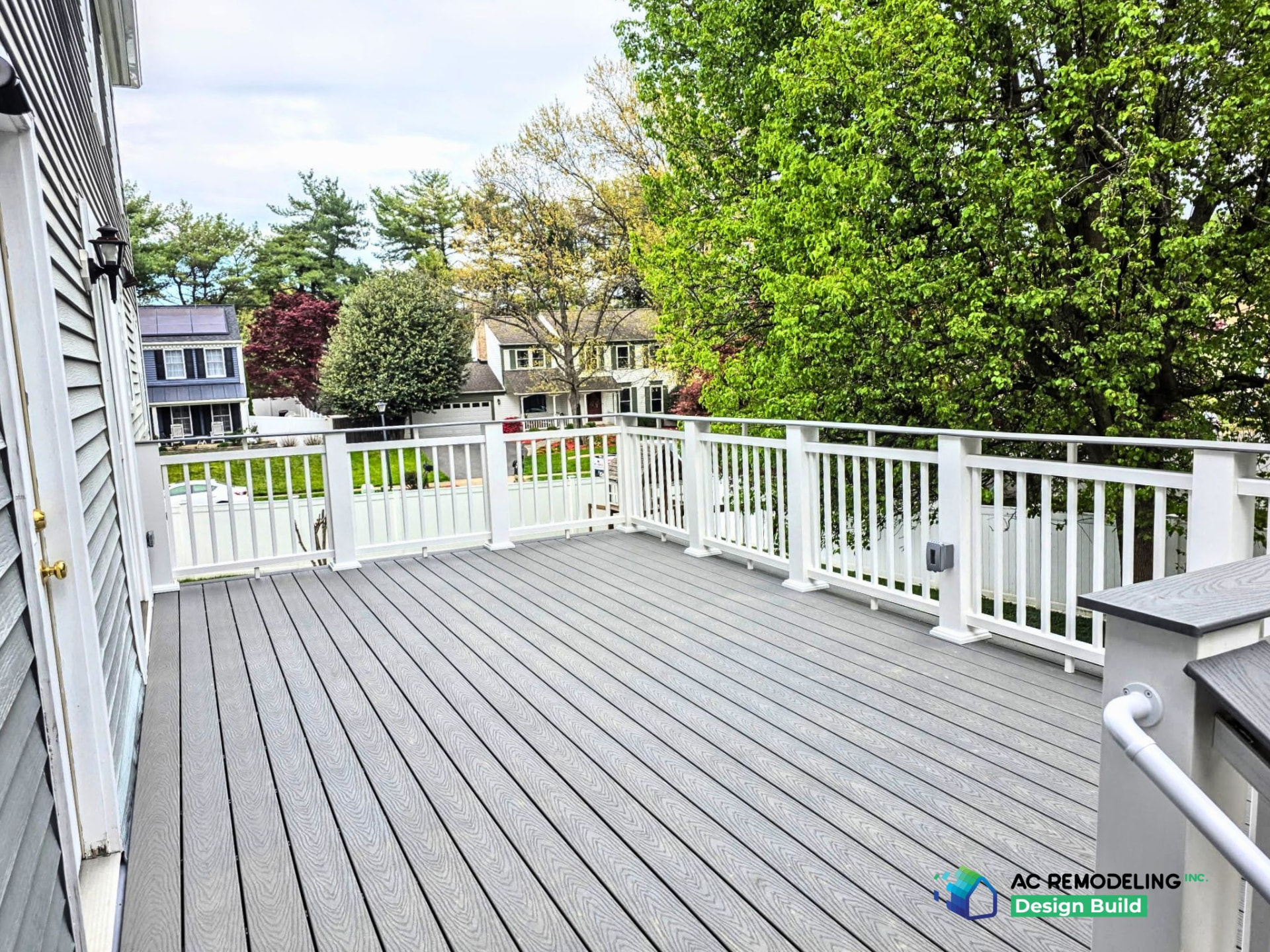 Gray composite deck flooring with white railing overlooking a backyard