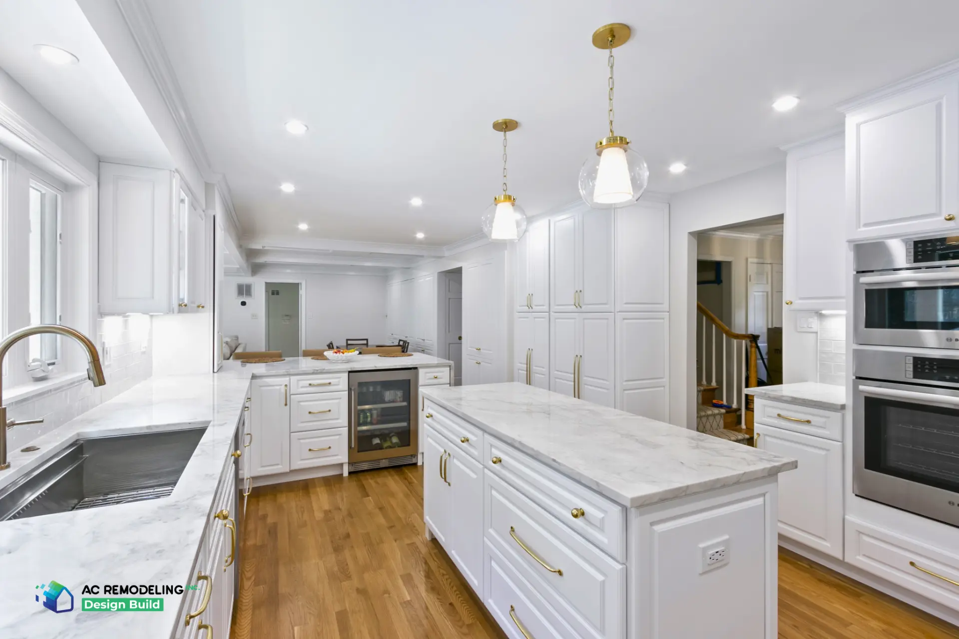 Galley kitchen with marble island, wine fridge and brass pendant lighting