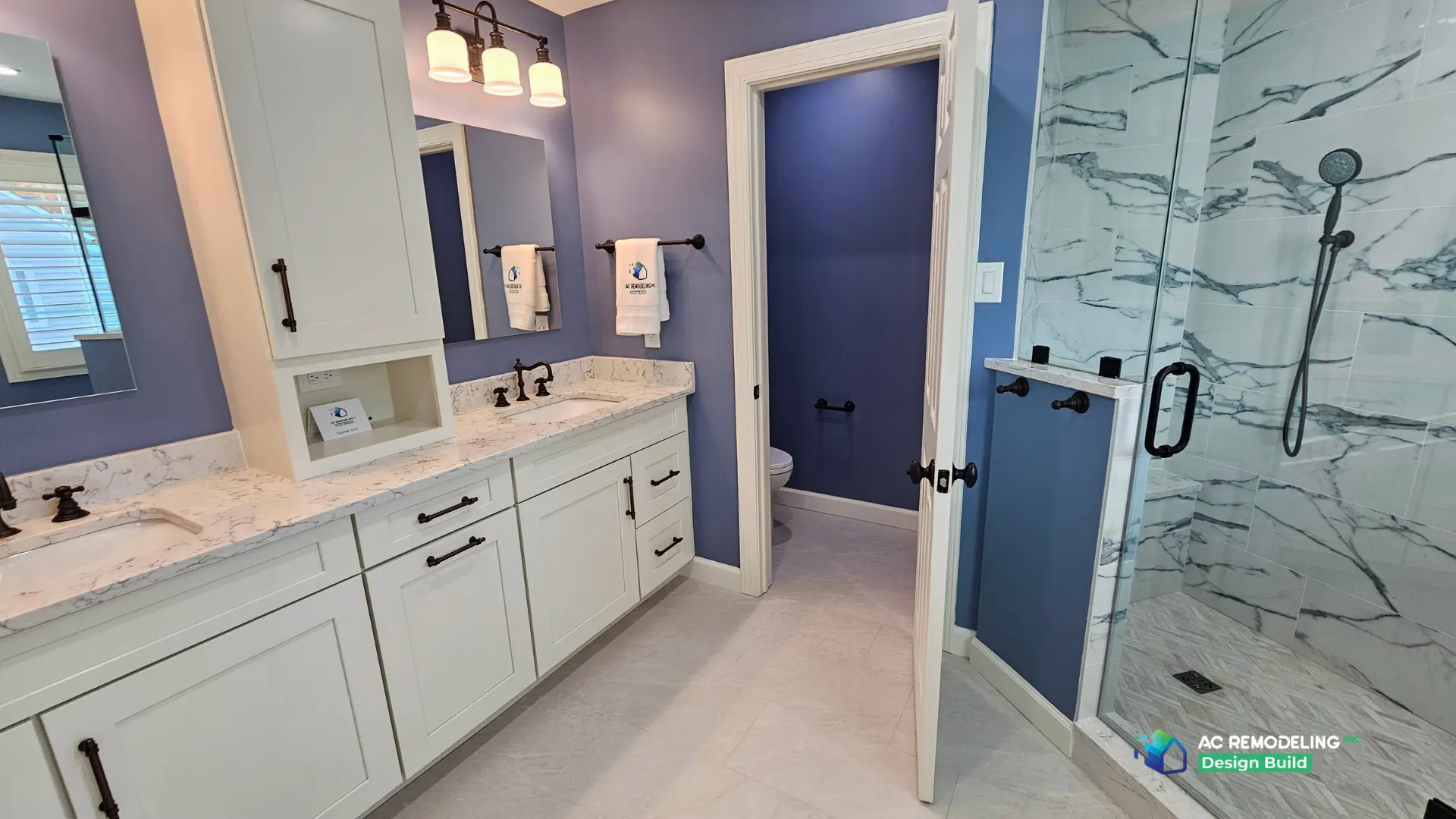 Wide view of the primary bath with double vanity, water closet and frameless marble shower