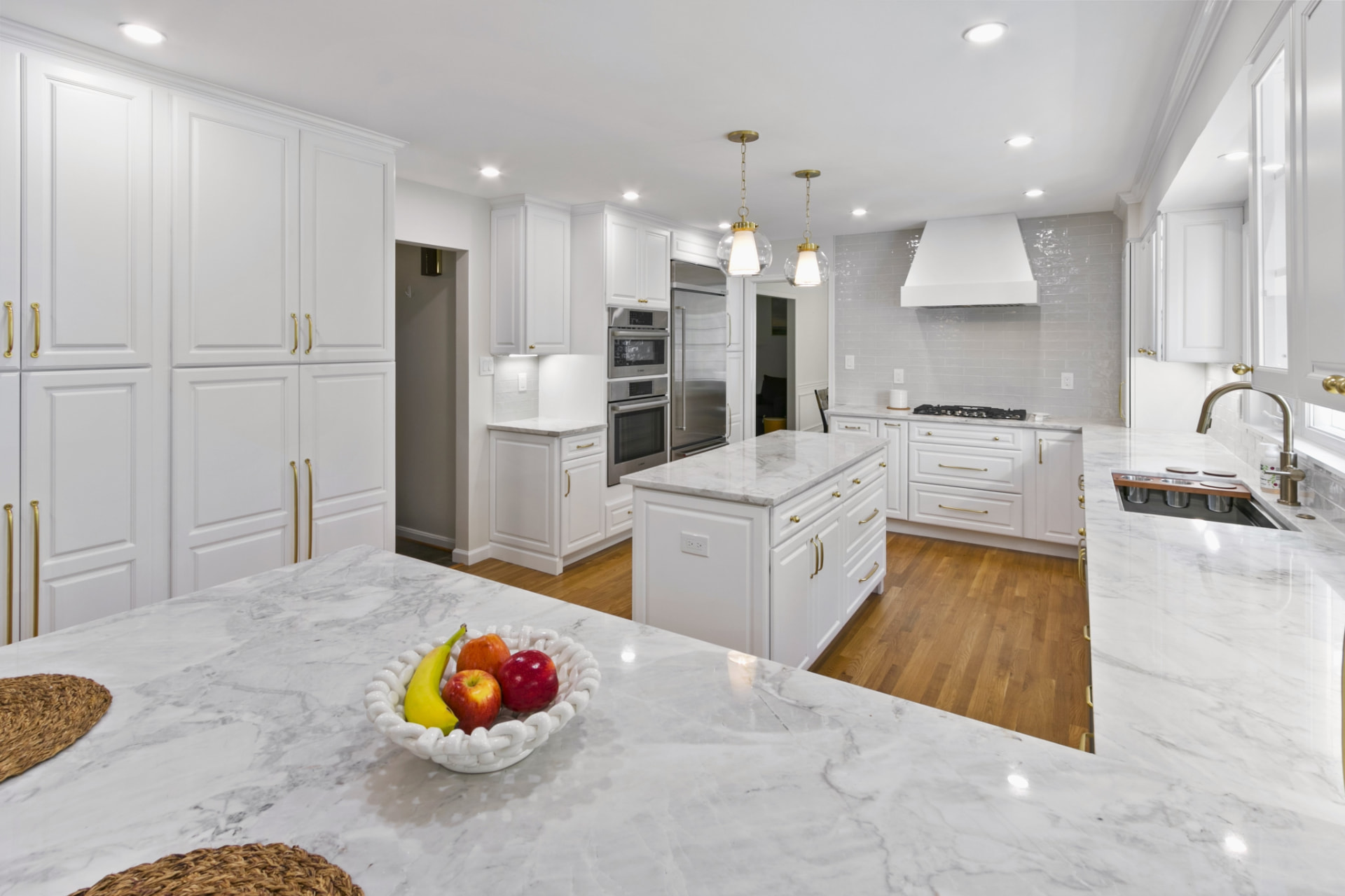 Remodeled Bethesda kitchen with quartz island, inset cabinetry and brass pendants