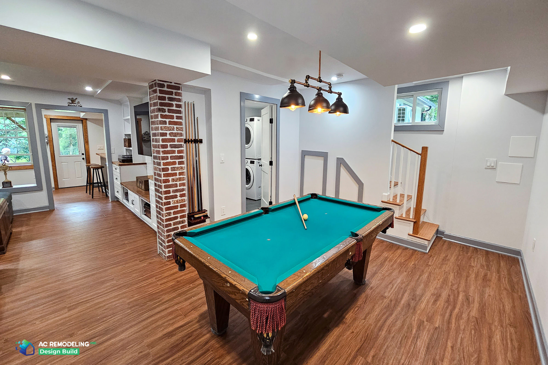 Luxe basement game room with billiards table, industrial pendant lighting, brick column and adjacent laundry room