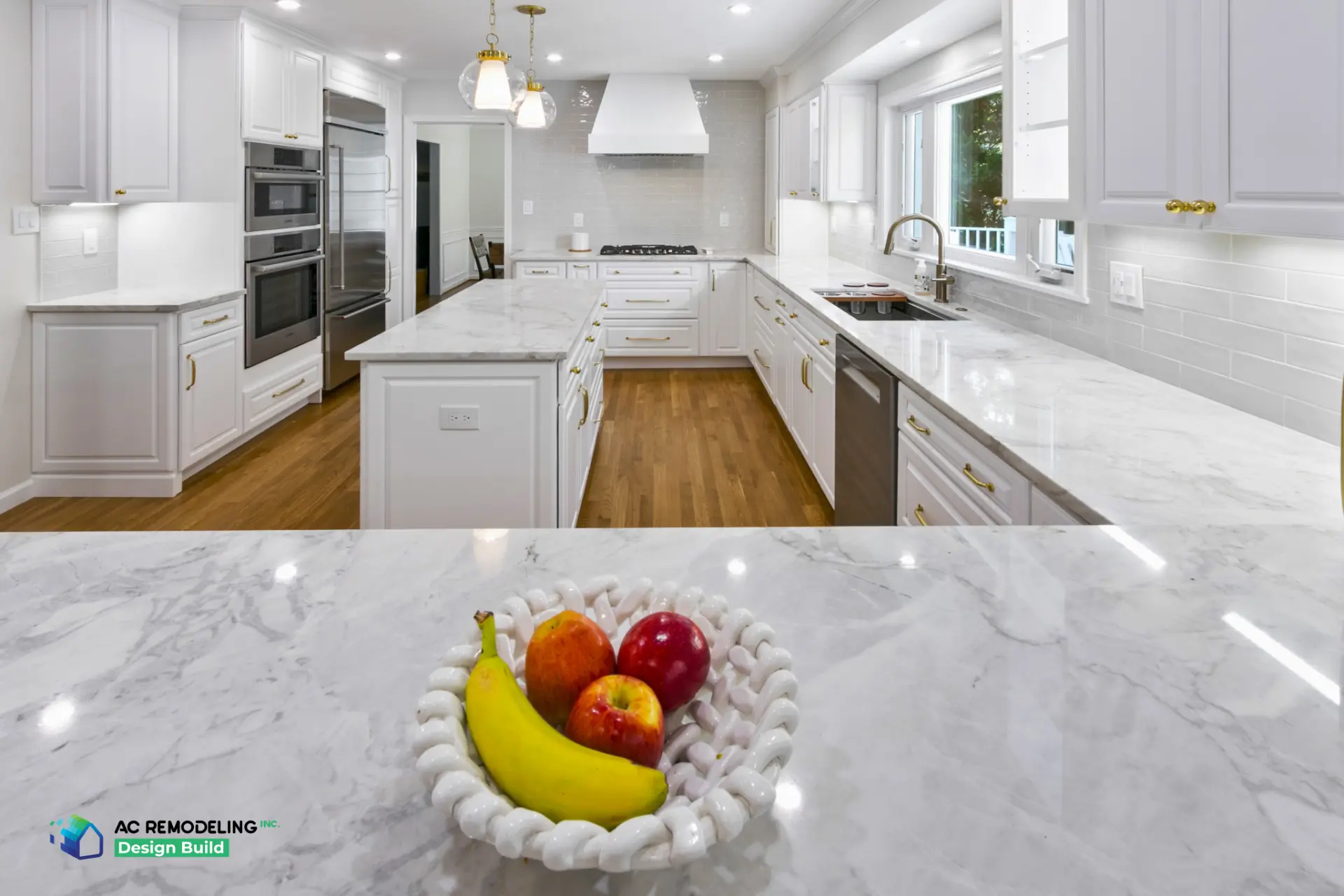 Long view of white kitchen with marble peninsula in foreground