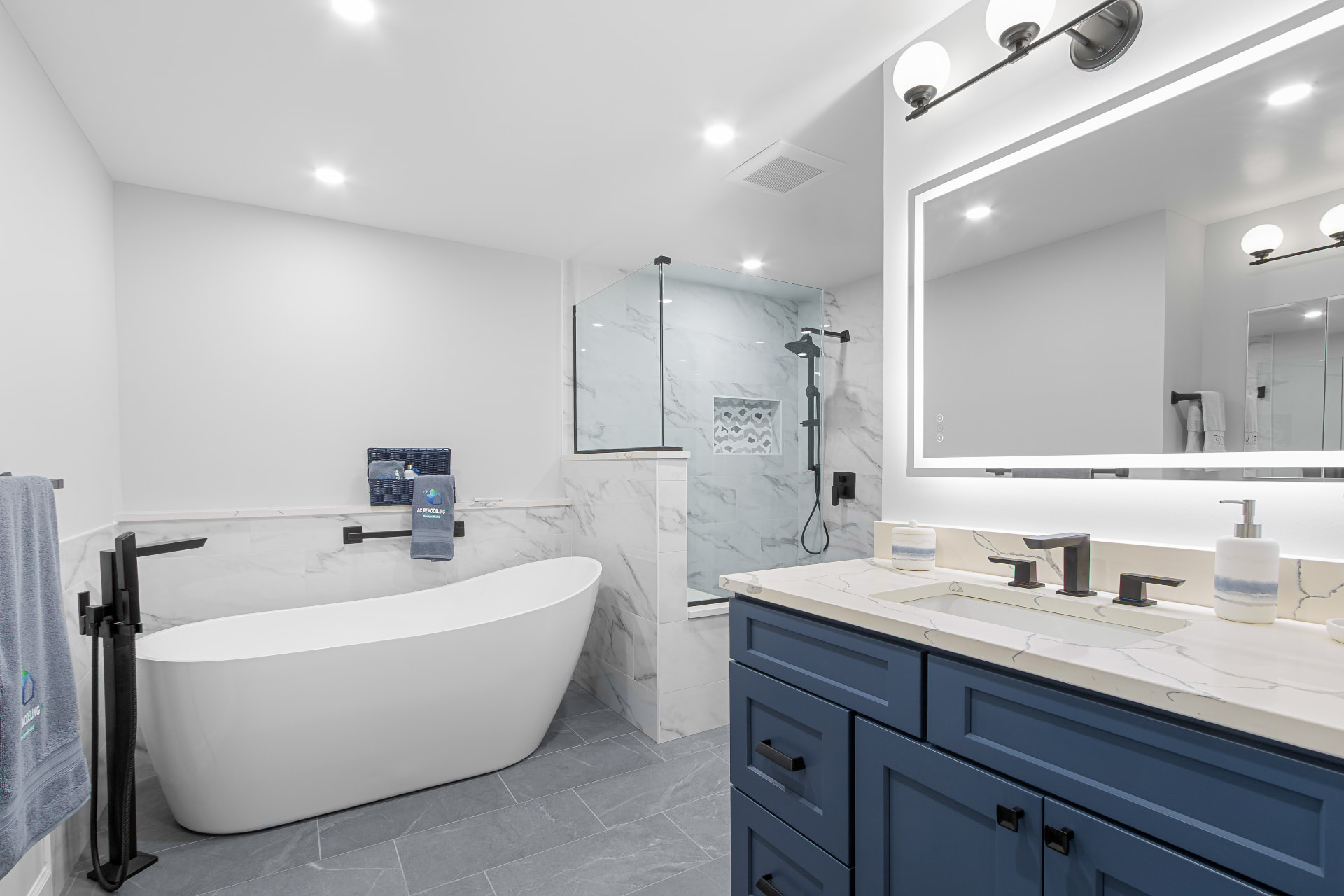 Remodeled bathroom with freestanding tub, marble tile shower and navy double vanity