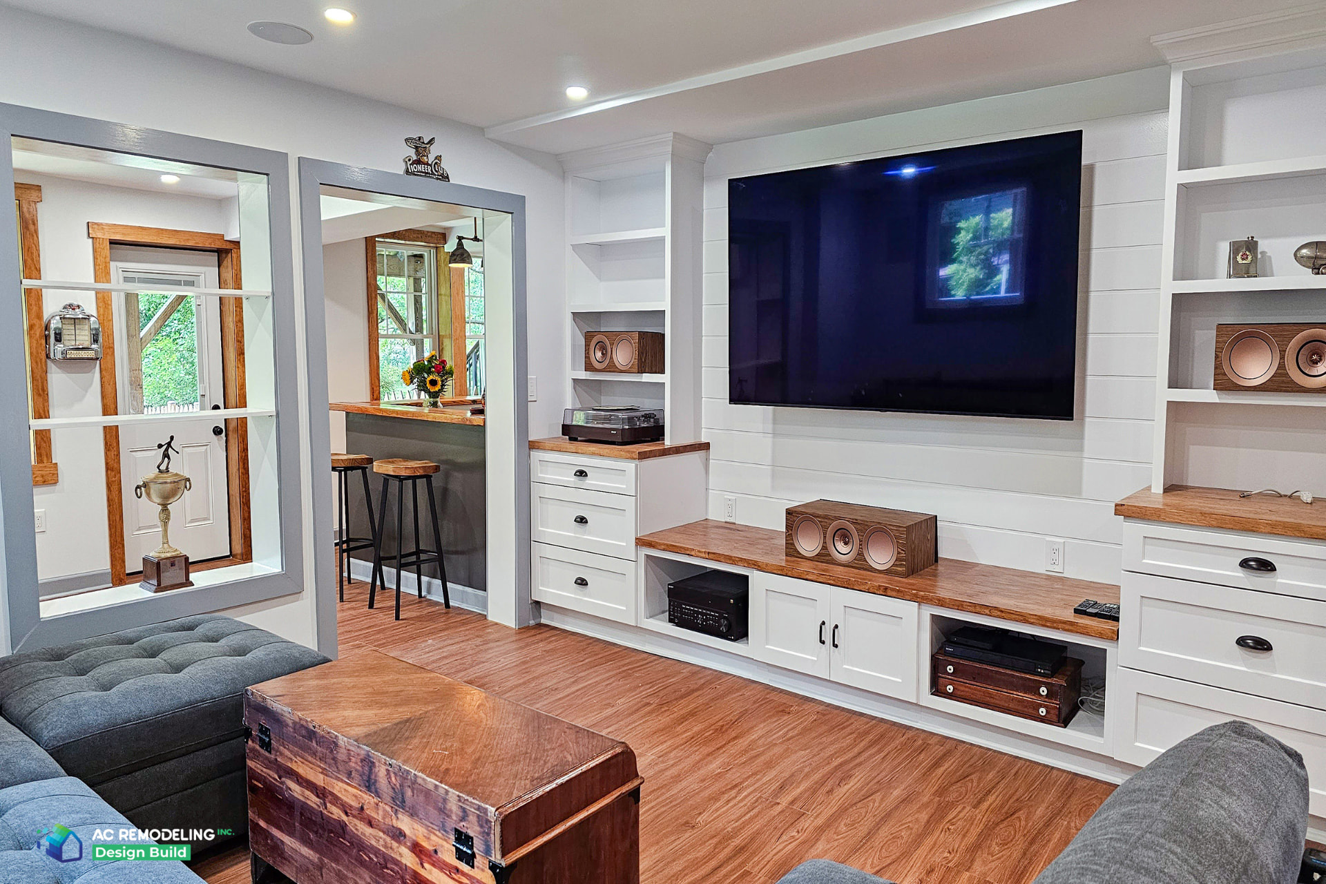Custom white basement entertainment center with shiplap TV wall, display shelving and integrated media storage