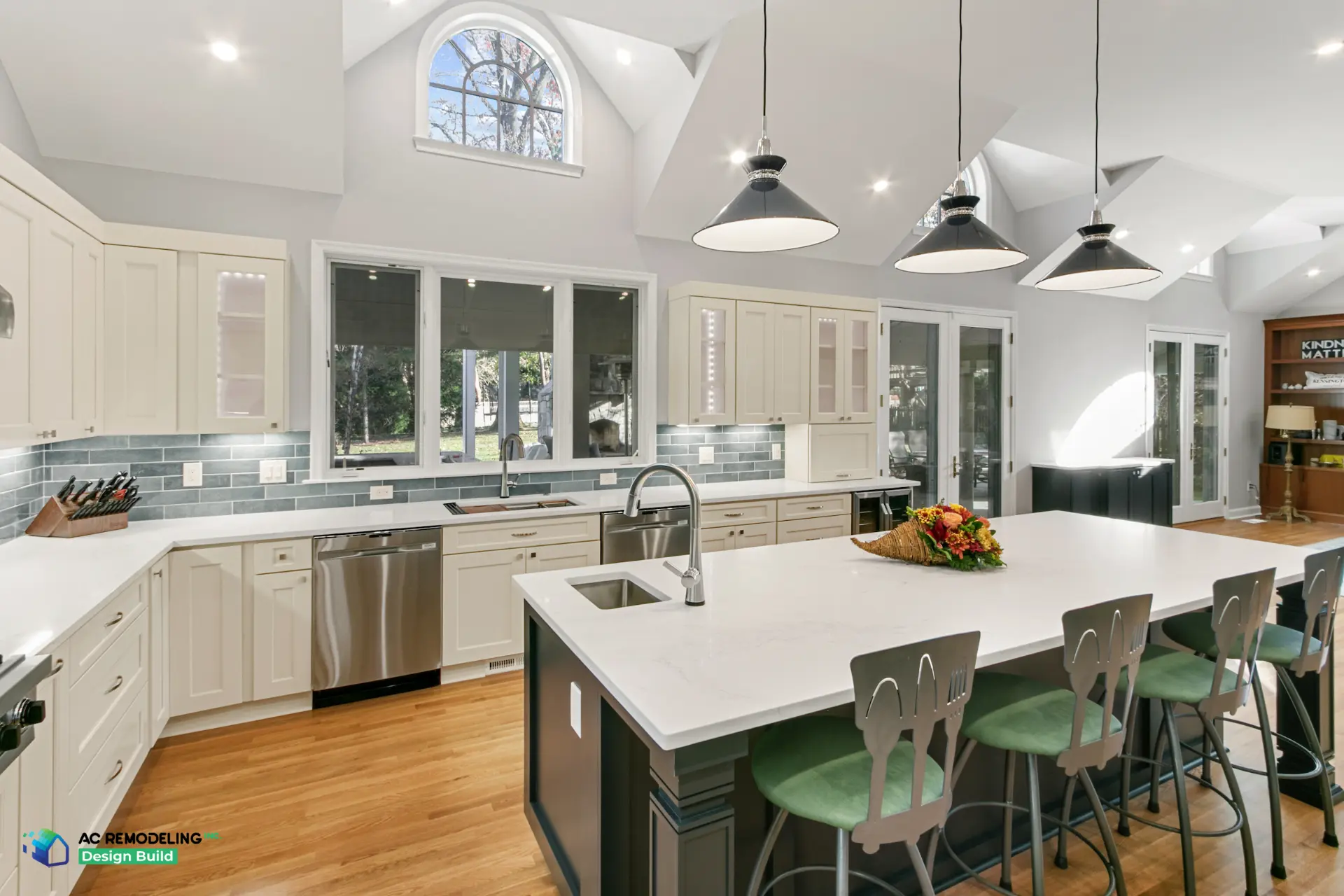 Open kitchen with long charcoal island, green stools and French doors to the porch