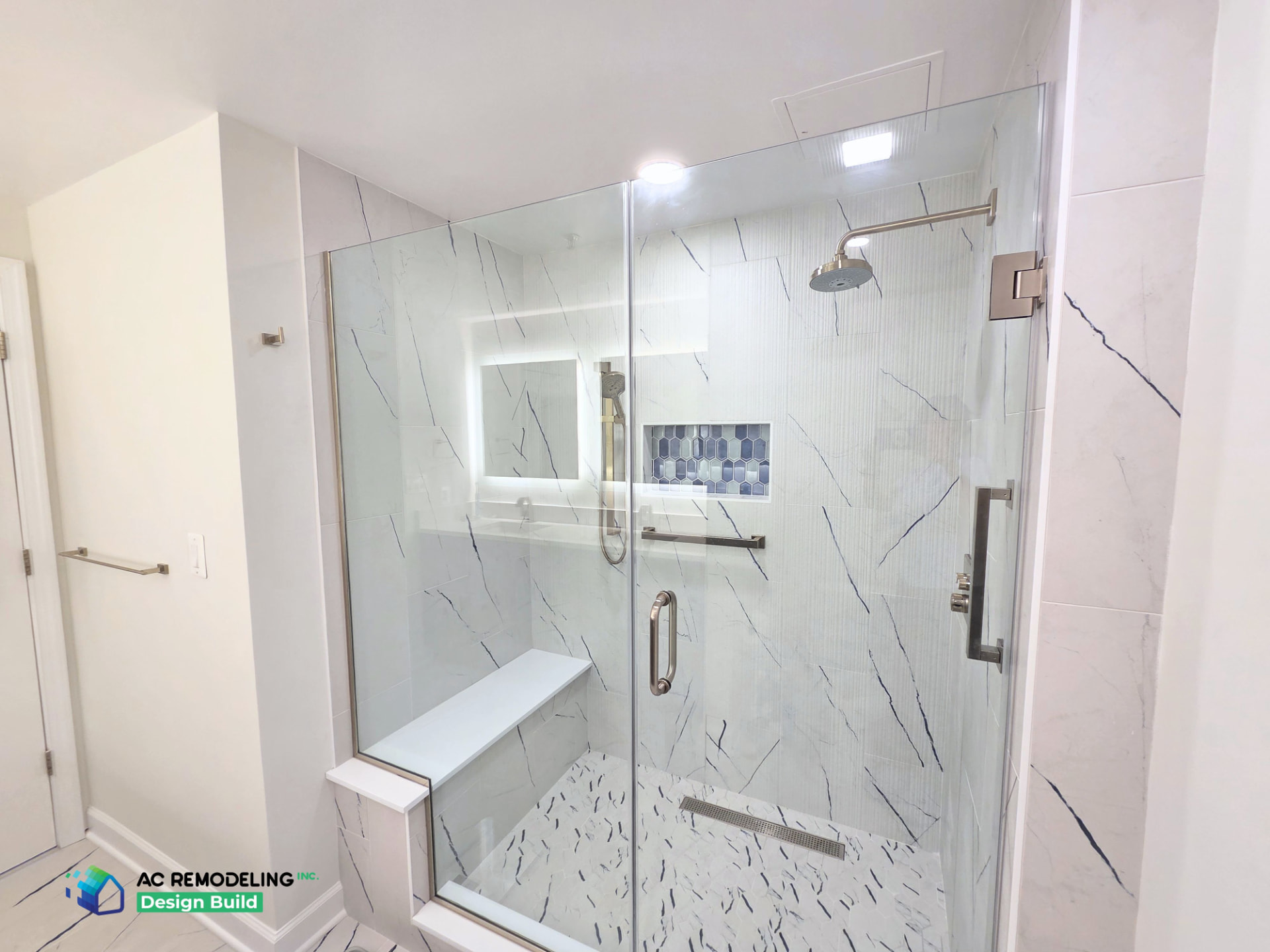 Frameless glass shower enclosure with bench, niche and backlit mirror reflection