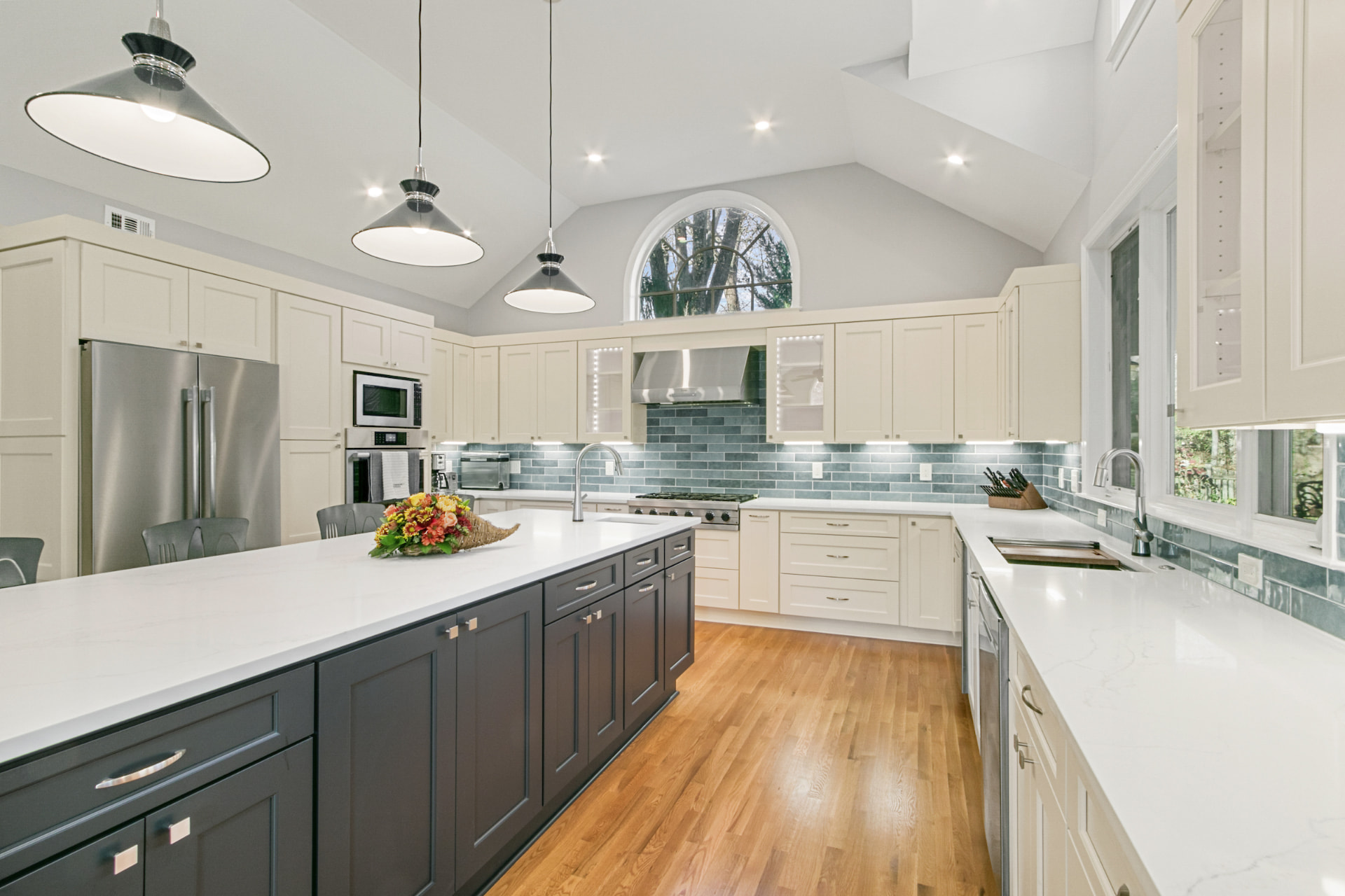 Vaulted remodeled kitchen with cream cabinets, charcoal island and sea-glass tile backsplash