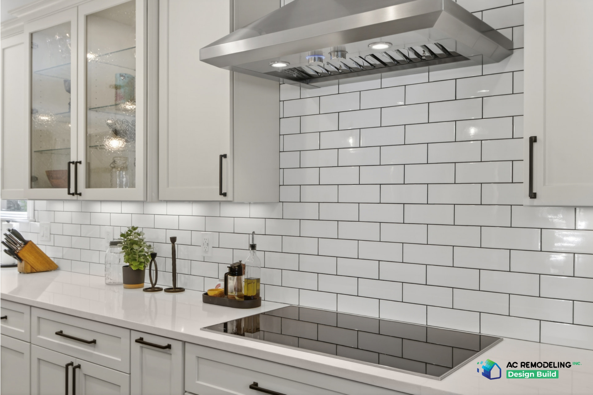 Detail of stainless hood, glossy white subway tile and induction cooktop