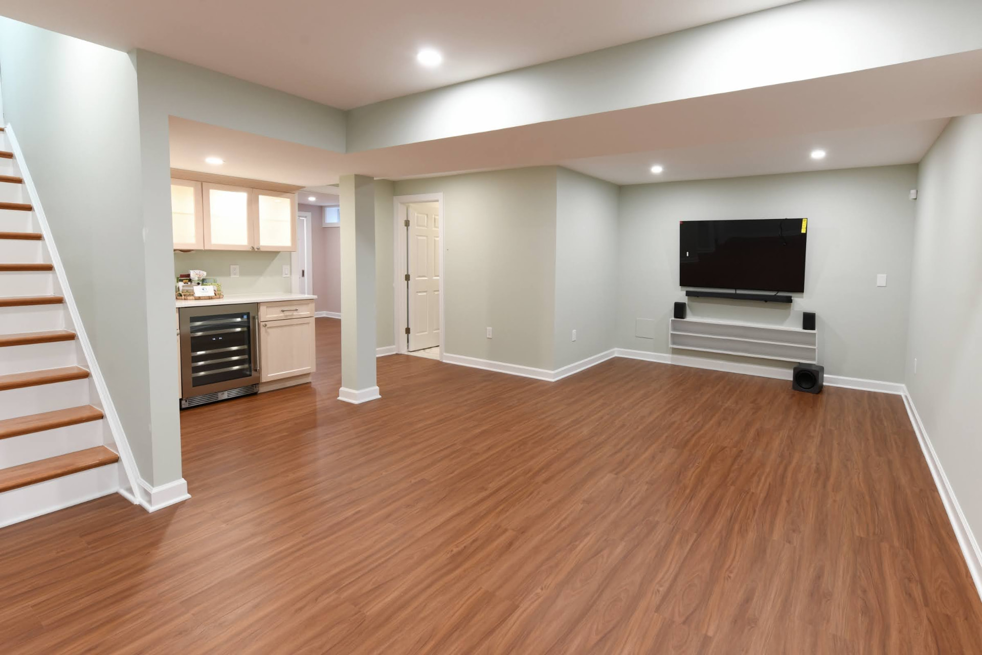 Finished basement with wet bar, wood-look flooring and mounted media wall