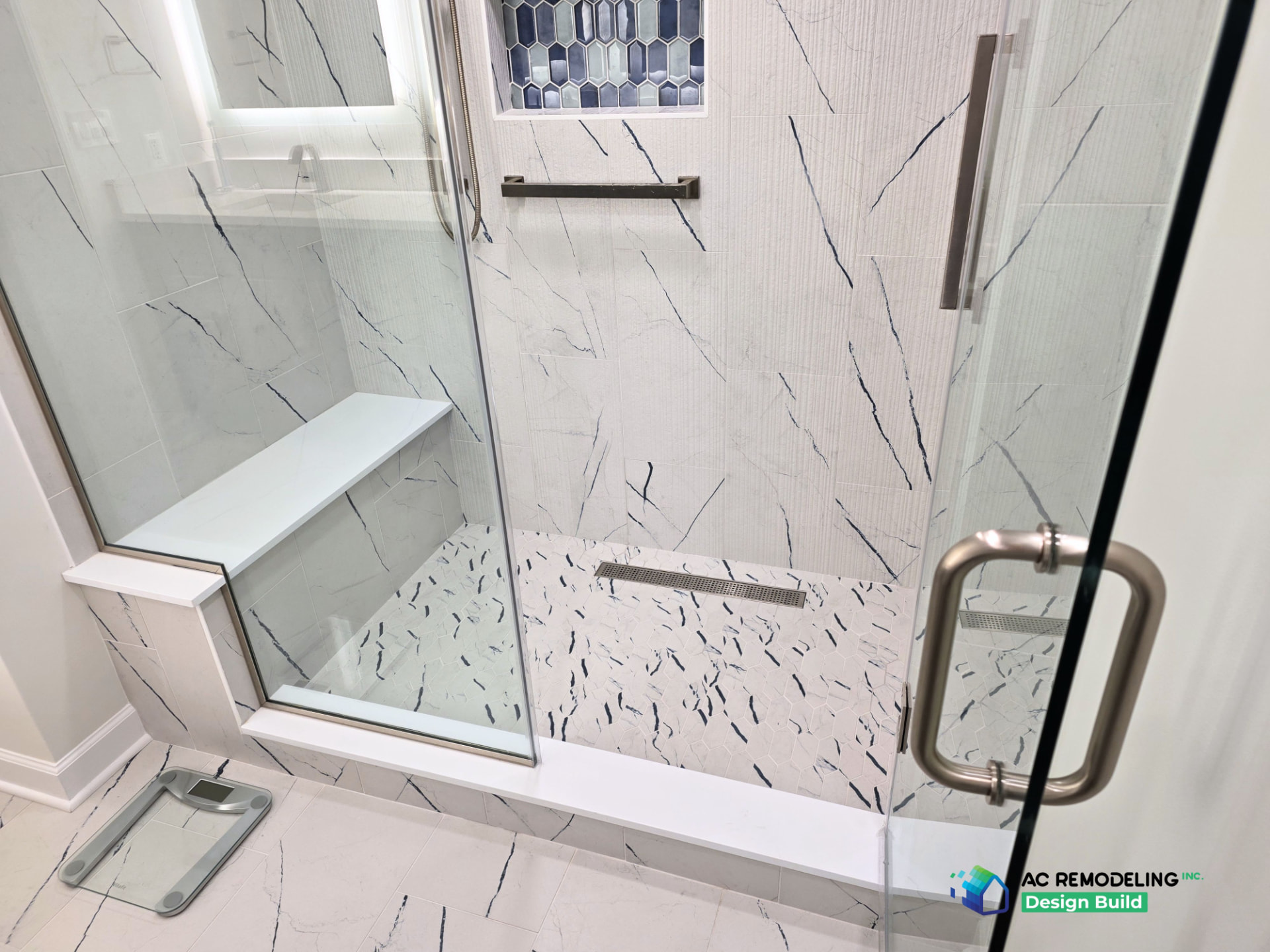 Marble-look shower with quartz bench, blue picket-tile niche and linear drain