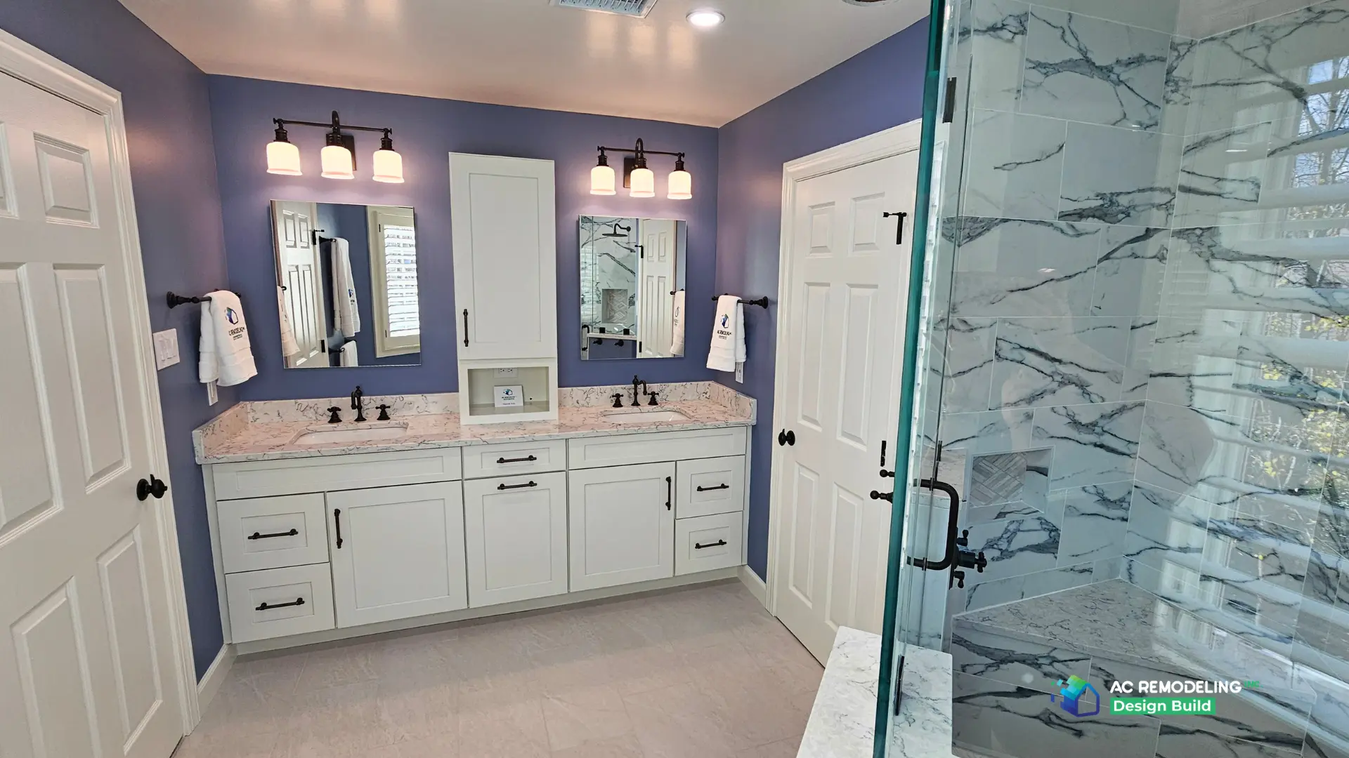 Double vanity opposite the marble-tiled shower with built-in bench
