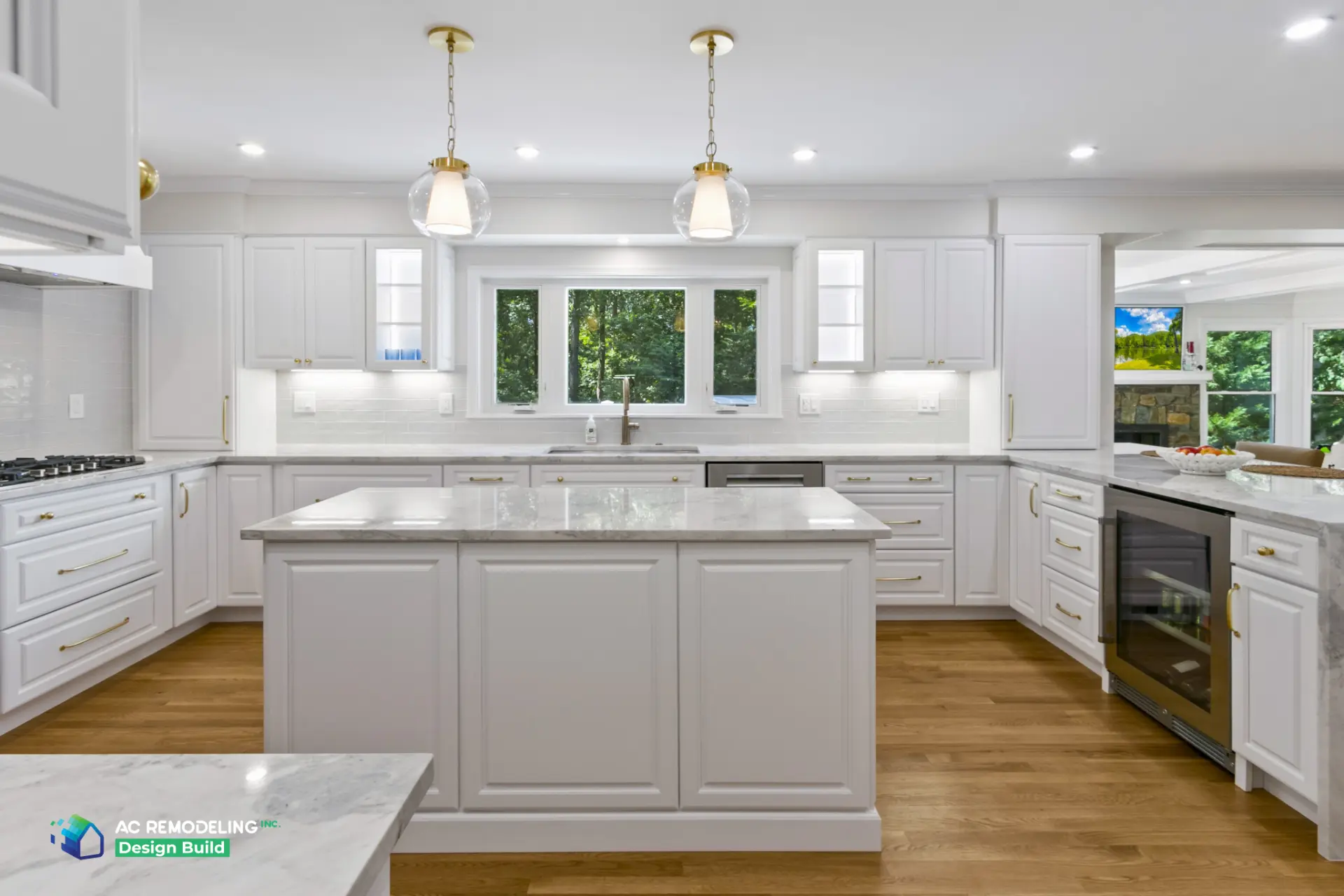Symmetrical white kitchen with window over sink and marble island