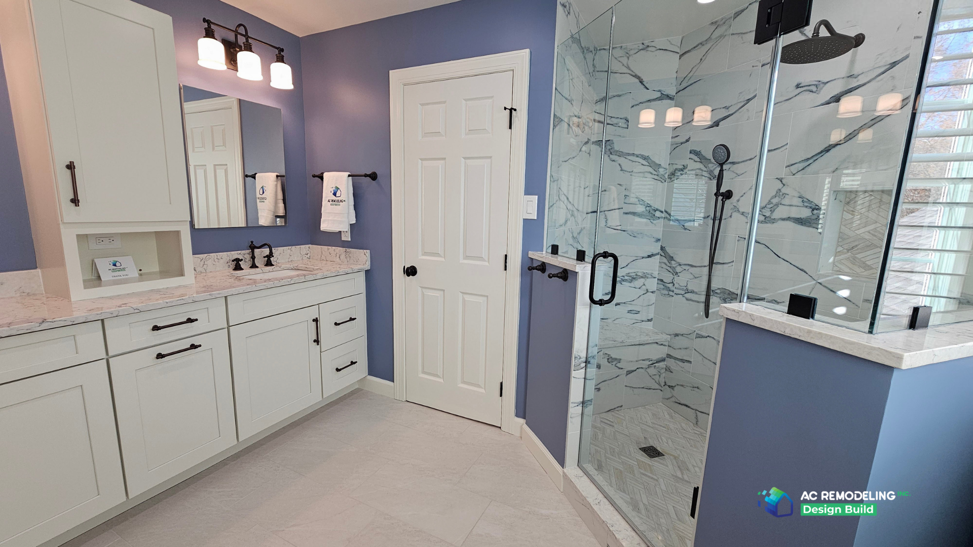 Vanity run with storage tower and outlet niche across from the frameless marble shower