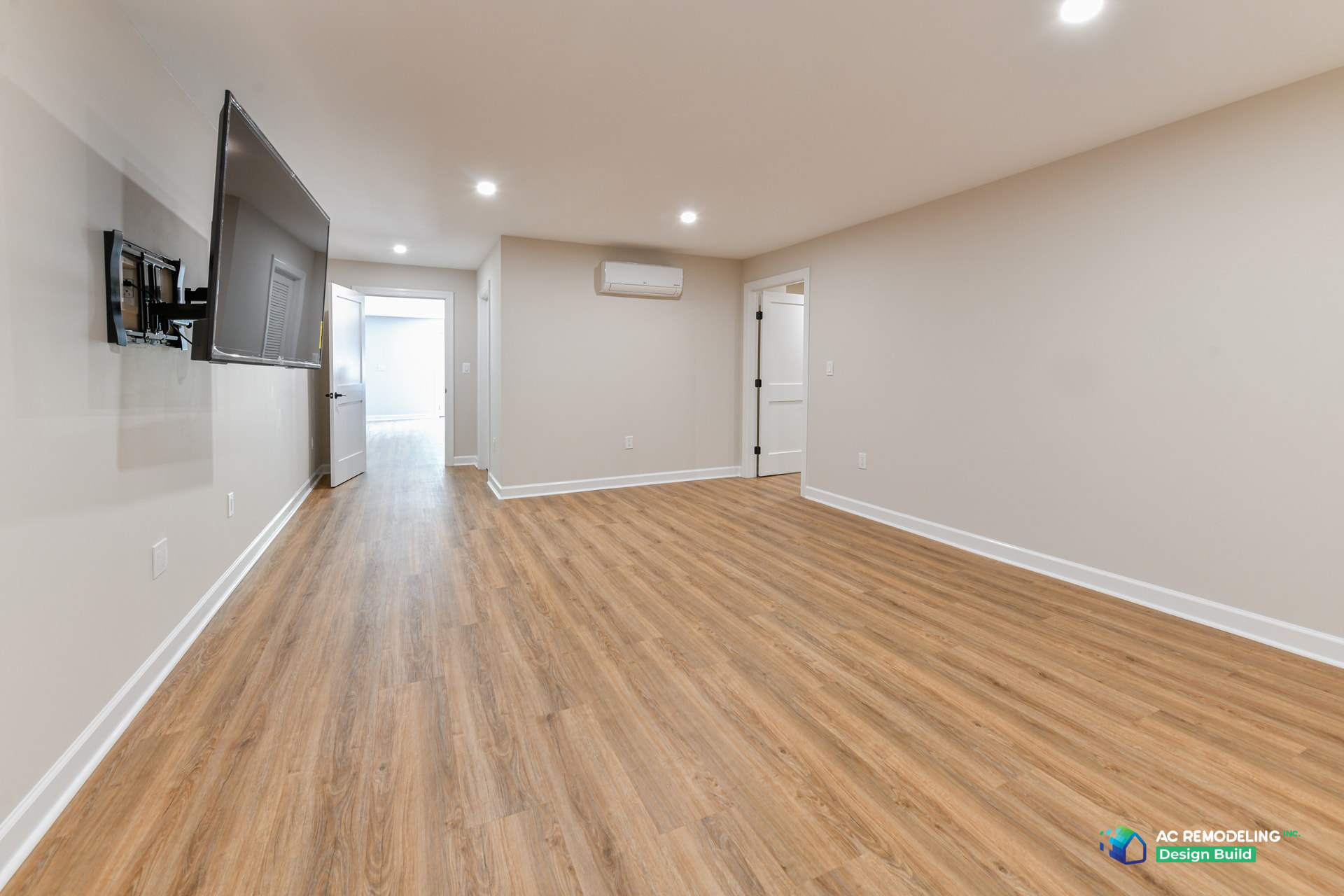 Finished basement media room in Rockville with wall-mounted TV, mini-split and warm wood-look flooring