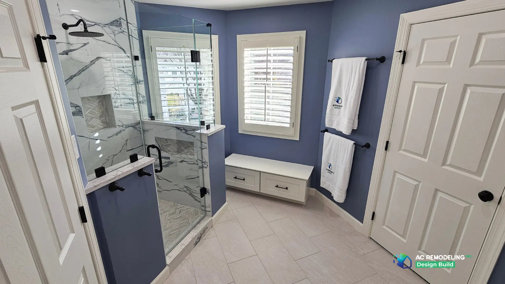 Wide view of the frameless corner shower, plantation shutters and white bench with drawers