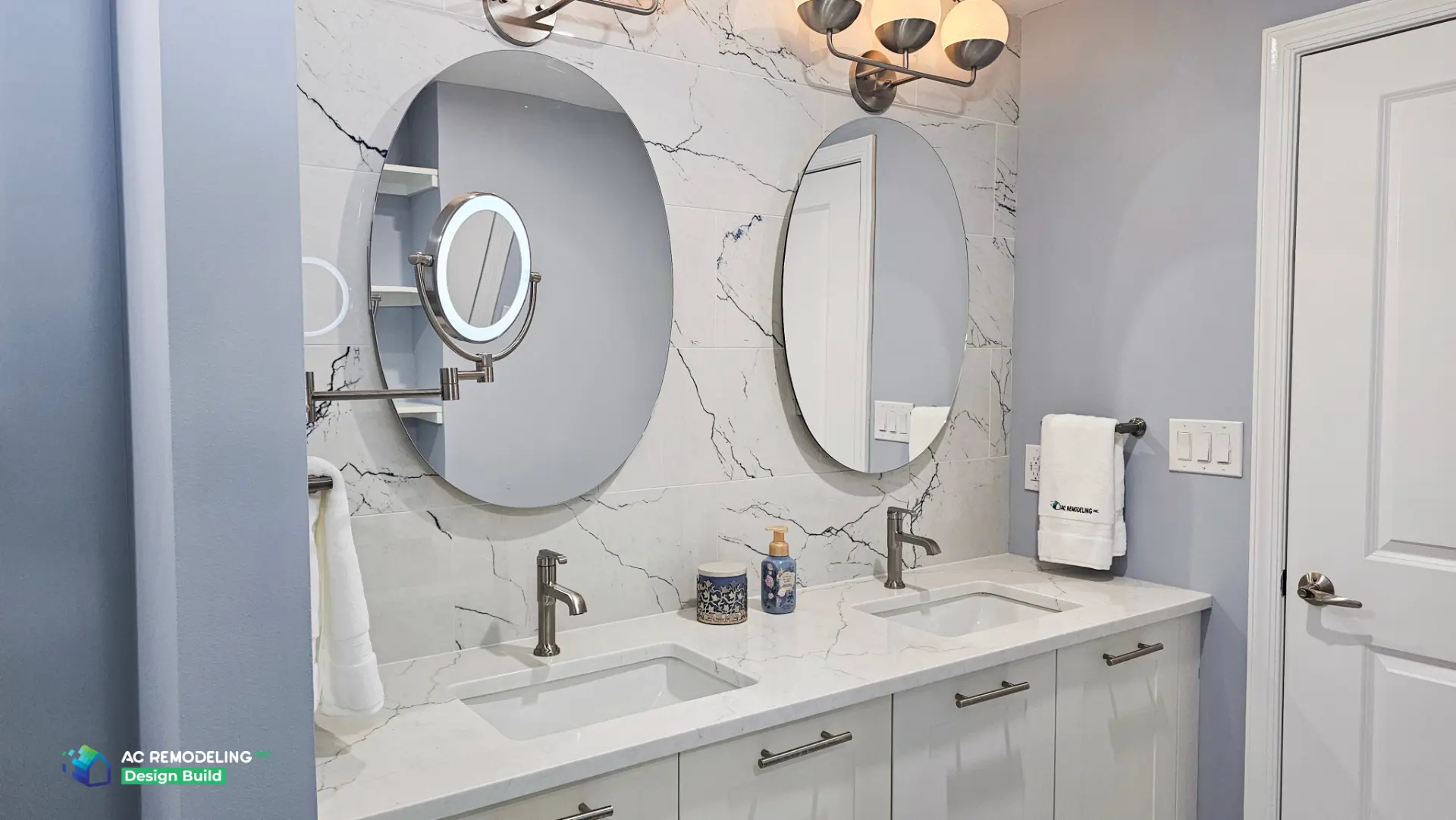 Oval mirrors and lit magnifying mirror above the white shaker double vanity
